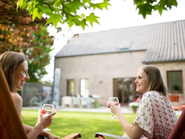 couple buvant un verre dans leur jardin devant leur maison