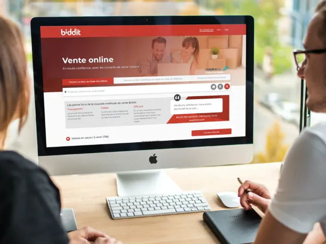 Un couple consulte le site internet de la plateforme de vente de biens immobiliers en ligne Biddit.