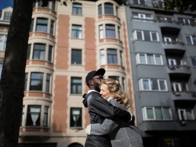 Un couple s'enlace devant un immeuble d'appartements à France.
