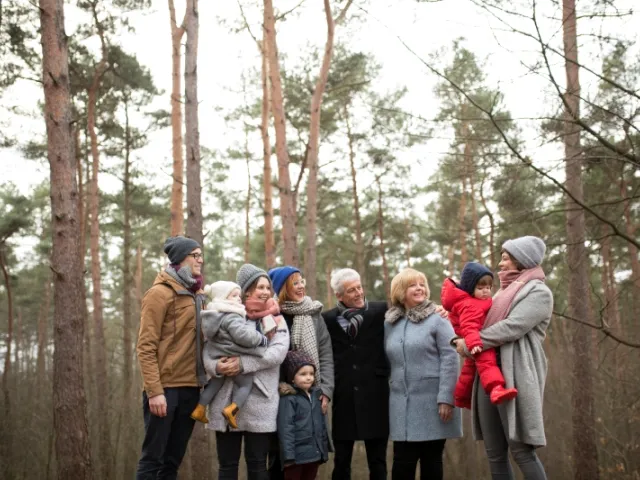 Une famille (grands-parents, enfants et petits-enfants) font une photo tous ensemble en forêt.
