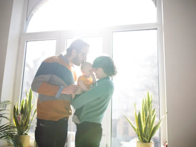 Un couple embrasse leur enfant dans leur habitation en France.