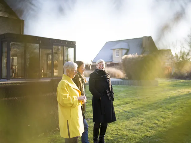 Trois générations de femmes discutent dans leur jardin d'une donation d'une maison en France.
