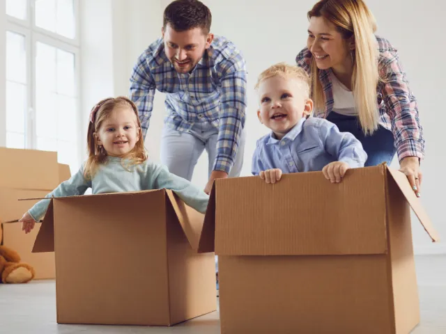 Un couple joue avec leurs deux enfants dans des caisses en carton après avoir acheté leur nouvelle maison en France.